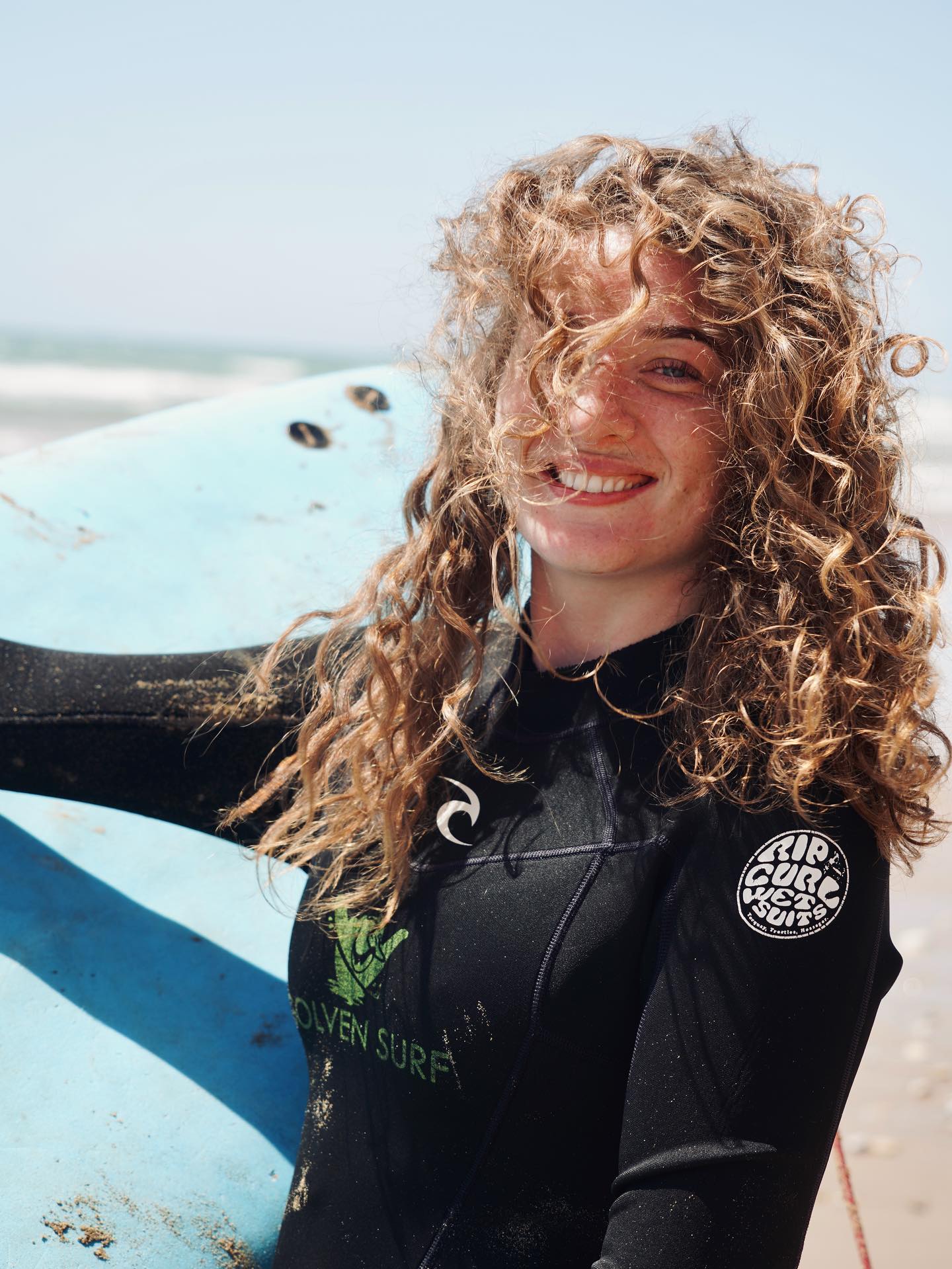 Uczestniczka surf campu pozuje z deską surfingową